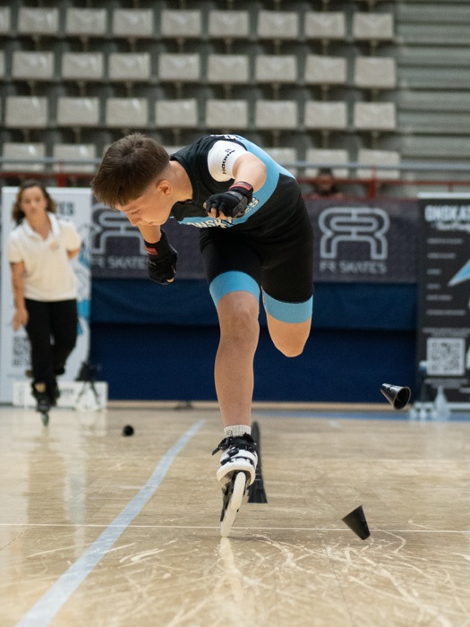 Patinador de Onskates impulsándose a una pierna sobre la línea de conos en una prueba de Speed Slalom